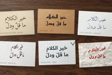 Six cartes sur un bureau en noyer, le même proverbe arabe composé dans six styles de police, l'une cochée au crayon