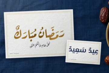 Cartes de vœux sur une nappe bleu nuit : « Ramadan moubarak » doré en Aref Ruqaa et « Aïd saïd » en El Messiri, près d’un plateau de dattes